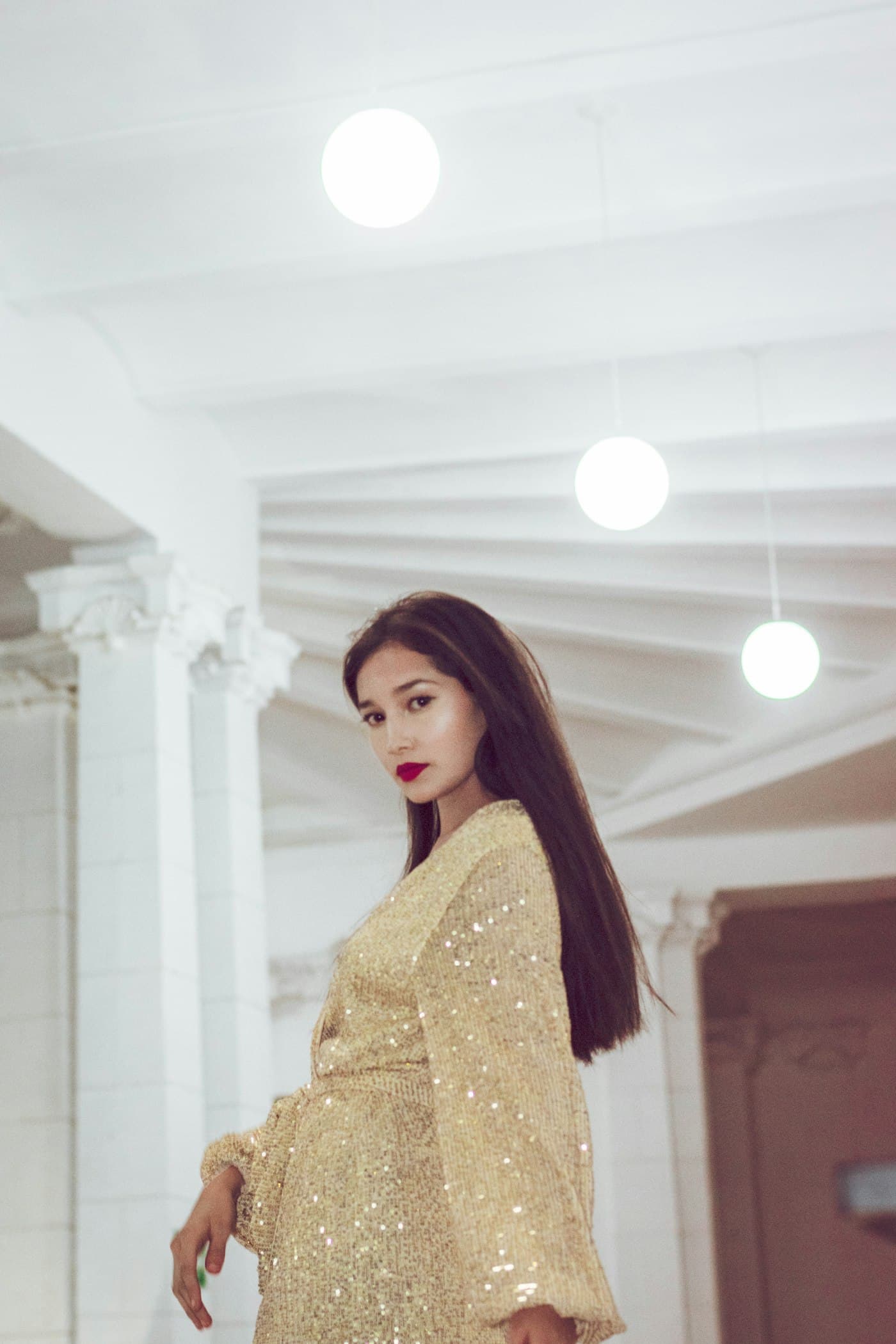 Model wearing a gold sequin dress from Sandra Glamz
